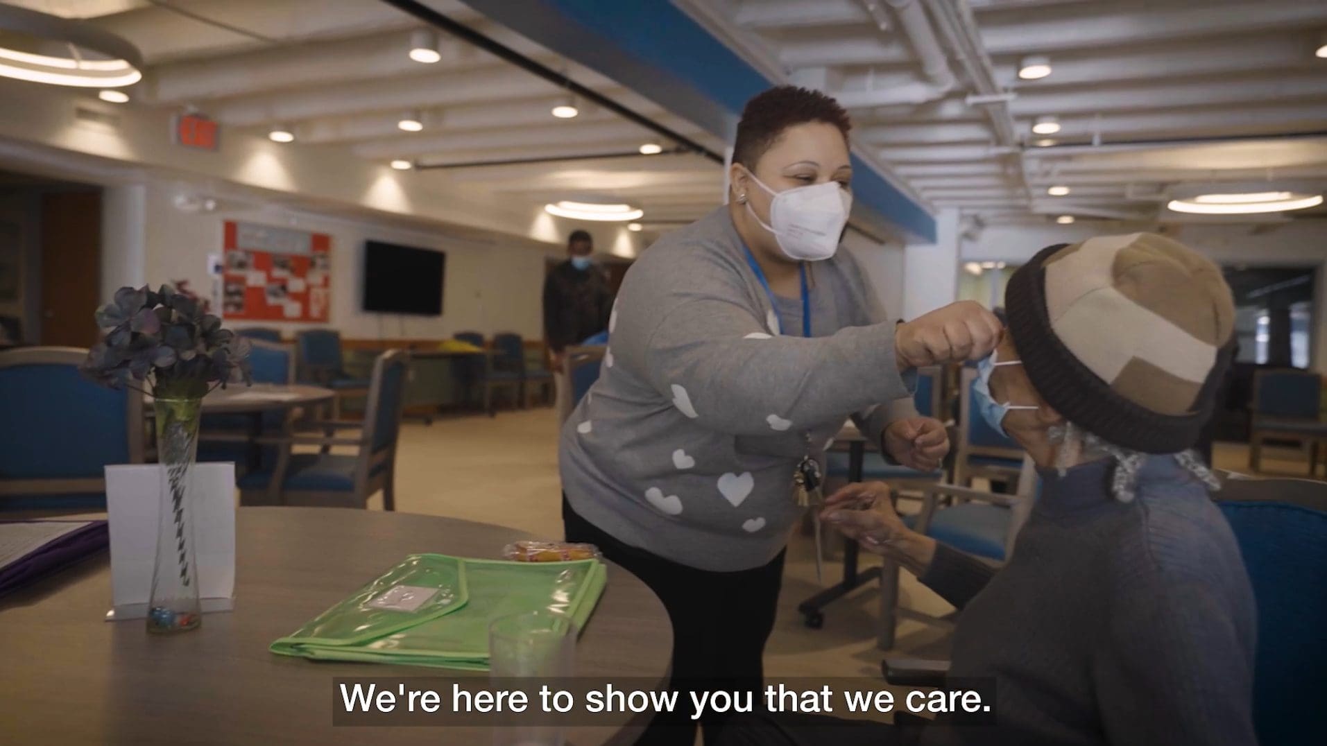 A young woman adjusts the mask of an older adult participant at Iona's Washington Home Center.